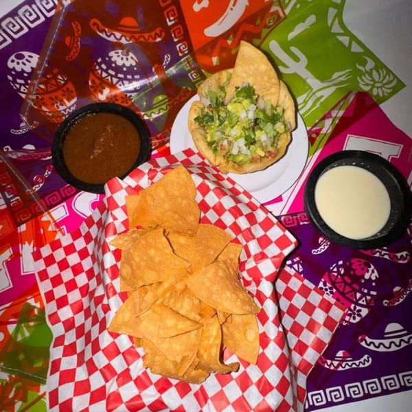 La Poblanita Mexican Restaurant's chips, salsa, queso, and a taco salad on a colorful Mexican-themed tablecloth.
